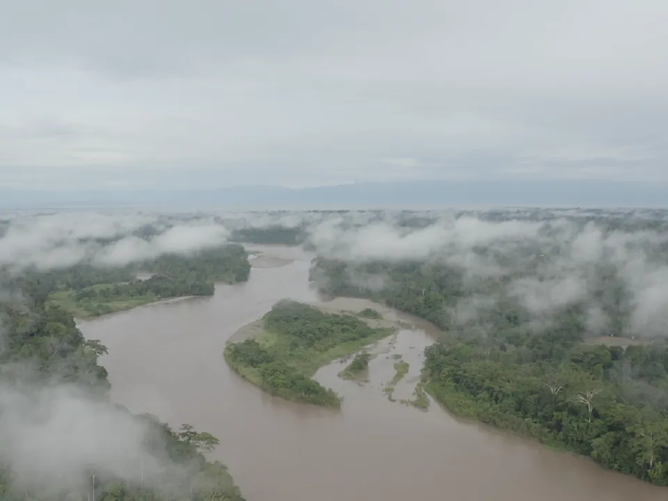 Vista aérea de un río serpenteando entre la selva del Putumayo, entre nubes bajas